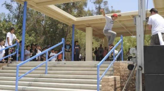 View of various people watching a person grind on a rail down a set of stairs in Paul Rodriguez Skate Park